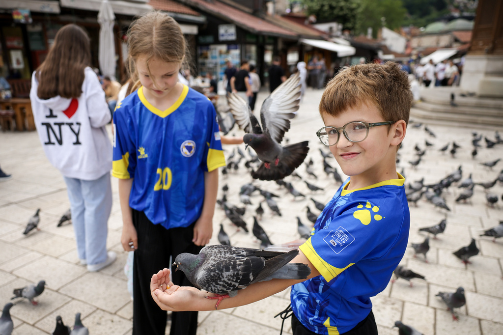 Children in Bosnian national soccer team jerseys feed pigeons in the old part of Sarajevo ahead of the soccer match of the FIFA World Cup 2026 between Canada and Bosnia, in Sarajevo, Bosnia, Friday, June 12, 2026. (AP Photo/Armin Durgut)