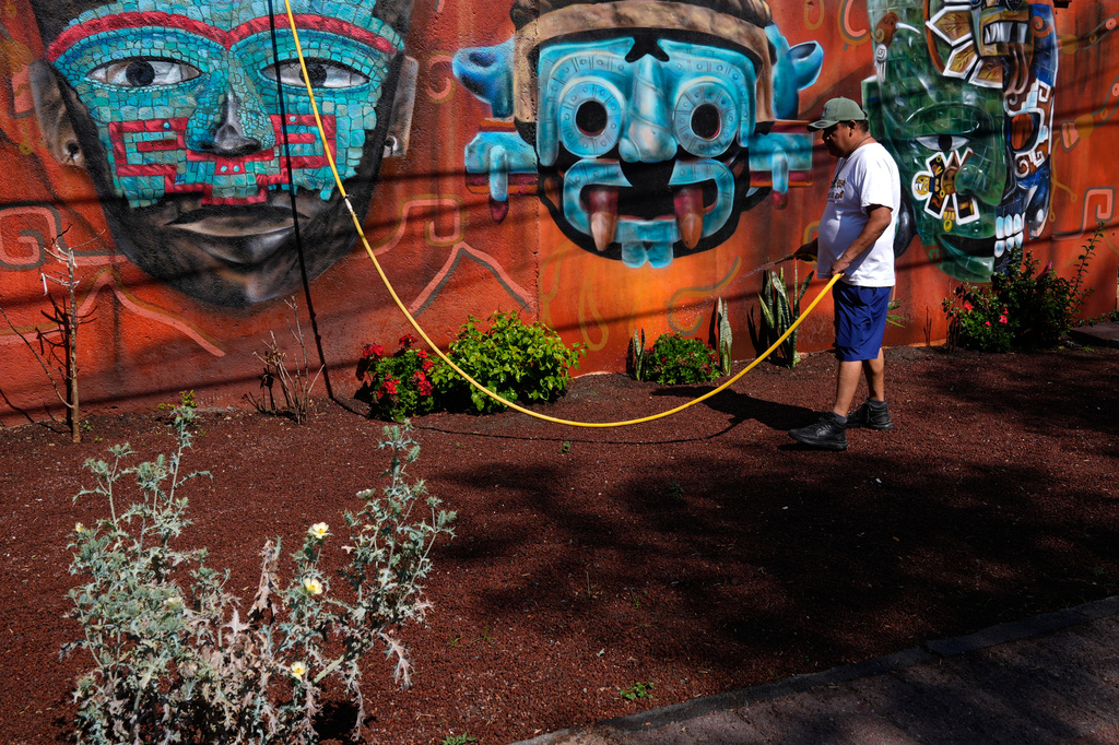 A man waters plants outside a handicrafts shop near the Teotihuacan pyramids, which remained closed a day after a gunman opened fire on tourists at the archaeological site outside Mexico City, Tuesday, April 21, 2026. (AP Photo/Marco Ugarte)