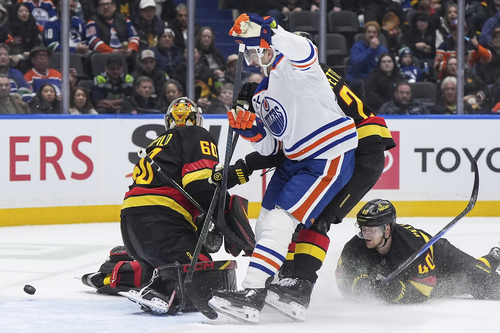 Edmonton Oilers' Zach Hyman, center, celebrates a goal by teammate Vasily Podkolzin, not seen, against Vancouver Canucks goalie Nikita Tolopilo (60) as Elias Pettersson (40) watches during the second period of an NHL hockey game, in Vancouver, British Columbia, on Saturday, Jan. 17, 2026. (Darryl Dyck/The Canadian Press via AP)