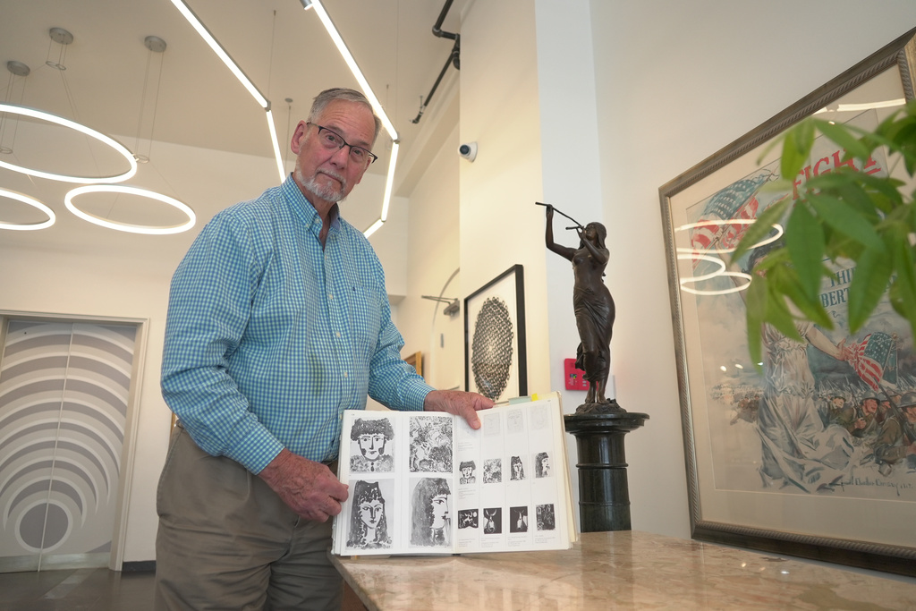 Art dealer Bill DeLind shows a picture of a Pablo Picasso sketch (upper left) stolen from his shop DeLind Fine Art Appraisals in 2018 in Milwaukee on Aug. 14, 2026. The sketch was recently found in town. (AP Photo/Laura Bargfeld)
