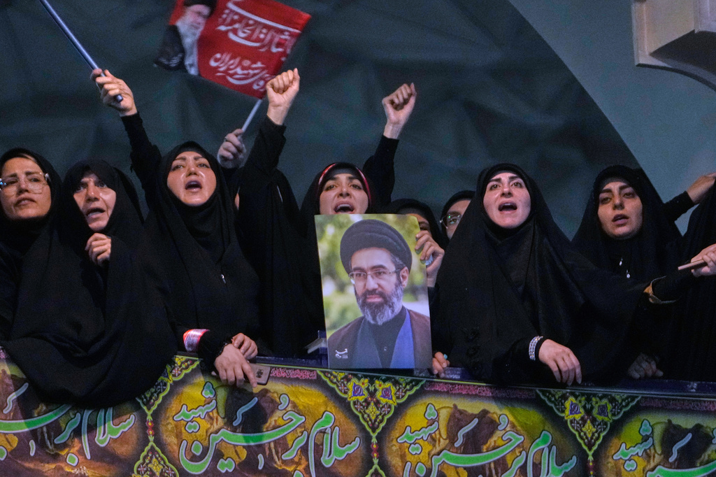 Mourners chant slogan as one of them holds a poster of the Supreme Leader Ayatollah Mojtaba Khamenei in a ceremony commemorating the late Supreme Leader Ayatollah Ali Khamenei at the Imam Khomeini Mosalla Grand Mosque in Tehran, Tuesday, July 14, 2026. (AP Photo/Vahid Salemi)