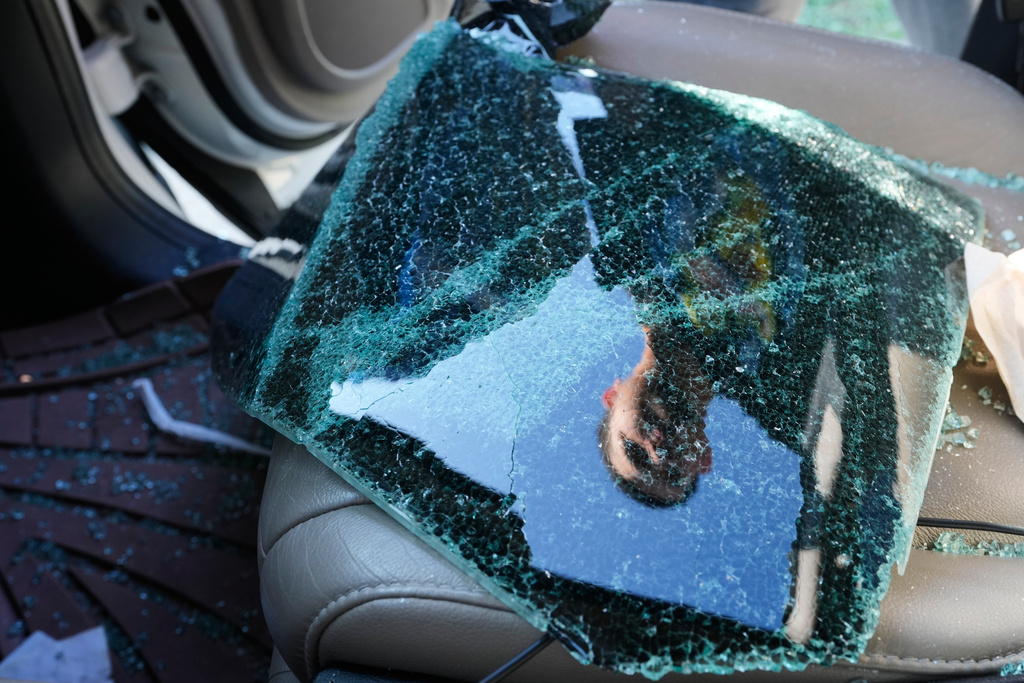 Jonathan Escalante stands over the broken window of his mother's car, which was shattered by federal immigration agents who took her away, during a federal immigration crackdown in Kenner, La., Tuesday, Dec. 9, 2025. (AP Photo/Gerald Herbert)