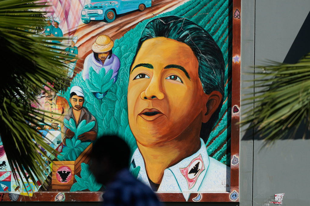 A pedestrian walks below an image of César Chavez on a mural in San Francisco, Wednesday, March 18, 2026. (AP Photo/Jeff Chiu)