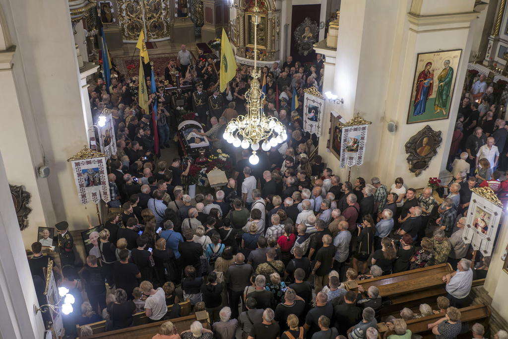 People mourn near the coffin of former Ukrainian parliament speaker Andriy Parubiy, who was killed last Saturday in Lviv, Ukraine, Tuesday, Sept. 2, 2025. (AP Photo/Vladyslav Musiienko)