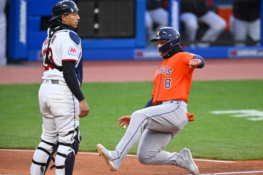 Cleveland Guardians catcher Bo Naylor, left, stands near home plate as Houston Astros' Christian Walker (8) scores in the fifth inning of a baseball game in Cleveland, Monday, April 20, 2026. (AP Photo/David Richard)