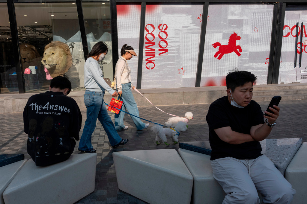 Women walk their dogs past a shopping street in Beijing, Friday, May 8, 2026. (AP Photo/Ng Han Guan)