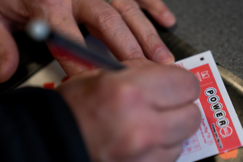 A person fills out a Powerball lottery ticket on Monday, Dec. 22, 2025, in Portland, Ore. (AP Photo/Jenny Kane)