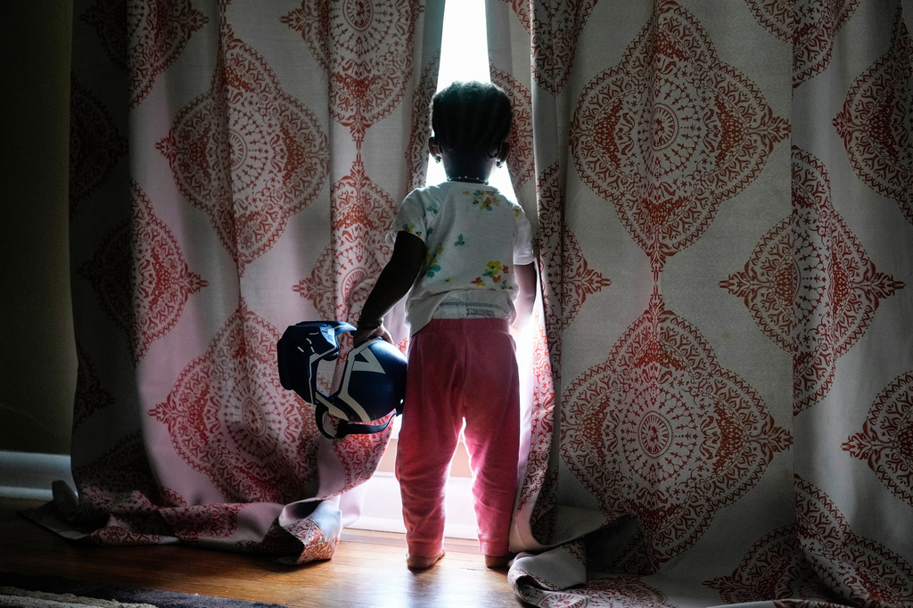 Khalidou Sy's young daughter looks out a window inside the family's home in Lockland, Ohio, Friday, July 31, 2026. (AP Photo/Carolyn Kaster)