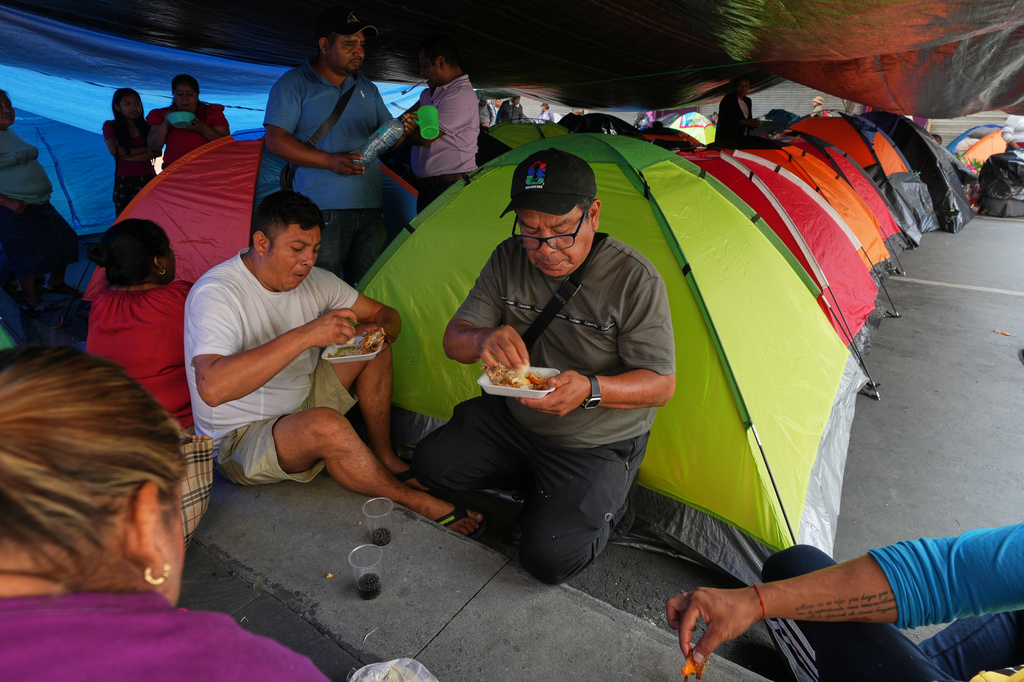 Teachers eat by tents they set up during protests to demand salary increases in Mexico City, Tuesday, June 2, 2026. (AP Photo/Marco Ugarte)