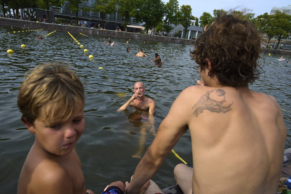 A smoker swims near the Maritime Museum during hot weather in Amsterdam, Netherlands, Wednesday, Aug. 13, 2025. (AP Photo/Peter Dejong)