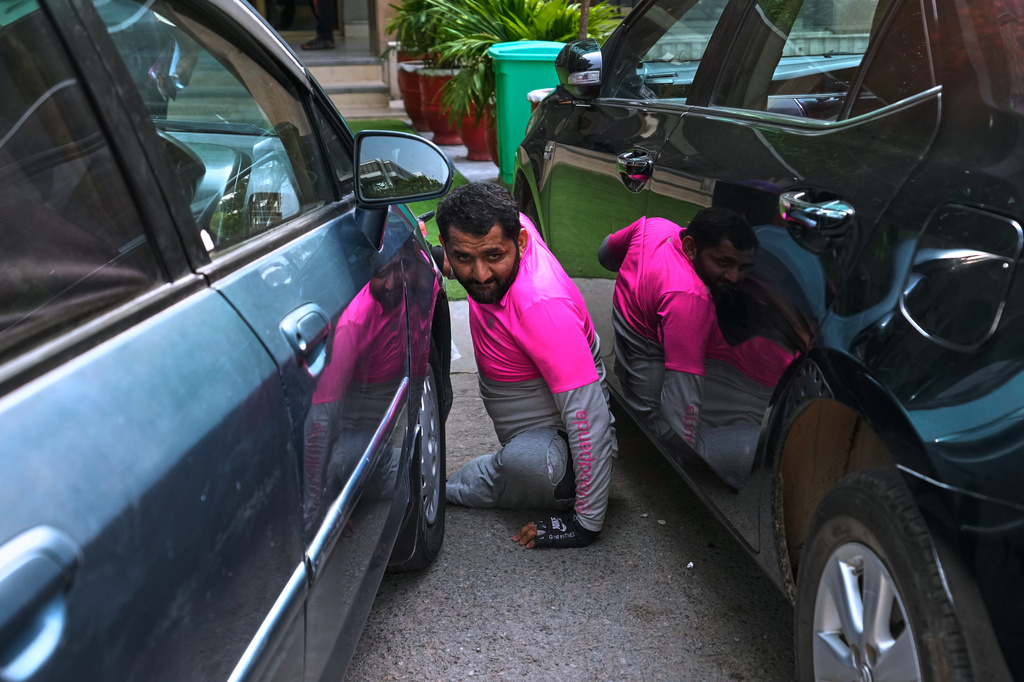 Hamza Ali, 28, who lost both legs in a road accident, navigates through parked cars after collecting a meal order from a food outlet for delivery in Islamabad, Pakistan, Friday, July 17, 2026. (AP Photo/Anjum Naveed)