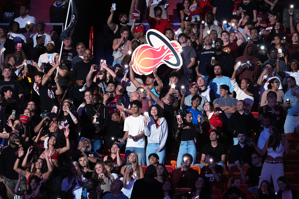Miami Heat fans cheer and sway in the stands along with the Heat dancers, bottom left, during a timeout in the second half of a preseason NBA basketball game against the San Antonio Spurs, Wednesday, Oct. 8, 2025, in Miami. (AP Photo/Rebecca Blackwell)