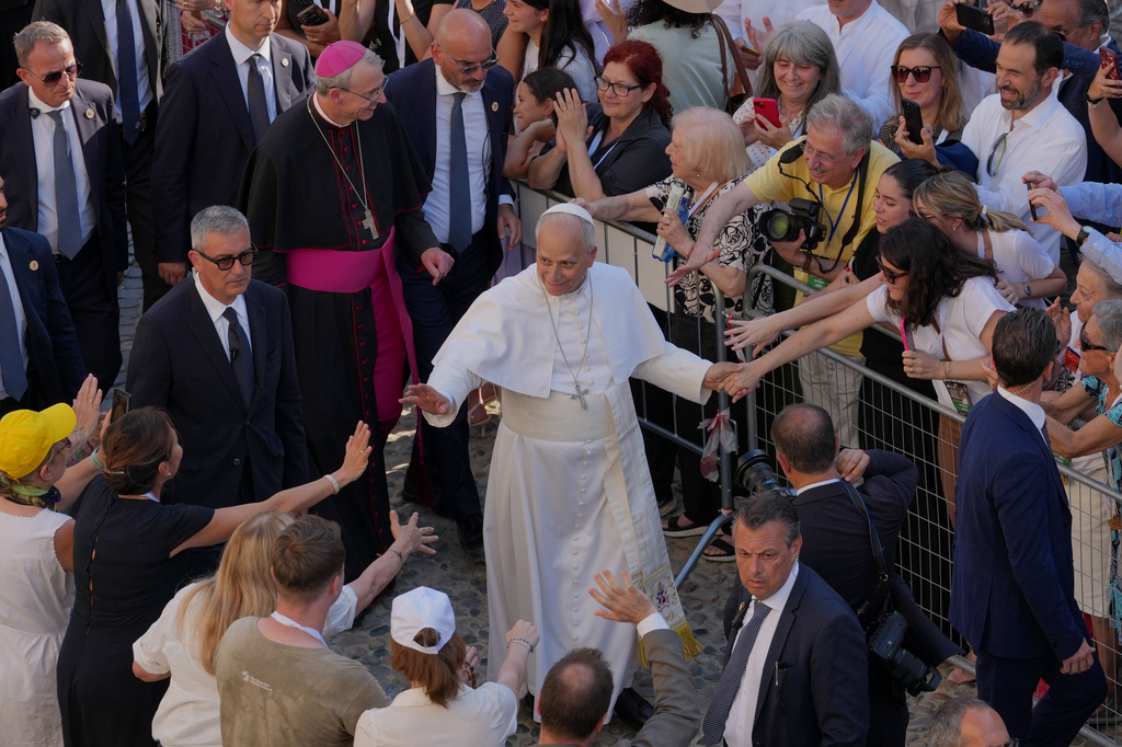 Faithful reach out to Pope Leo XIV as he leaves Pavia Cathedral in northern Italy, Saturday, June 20, 2026. (AP Photo/Antonio Calanni)