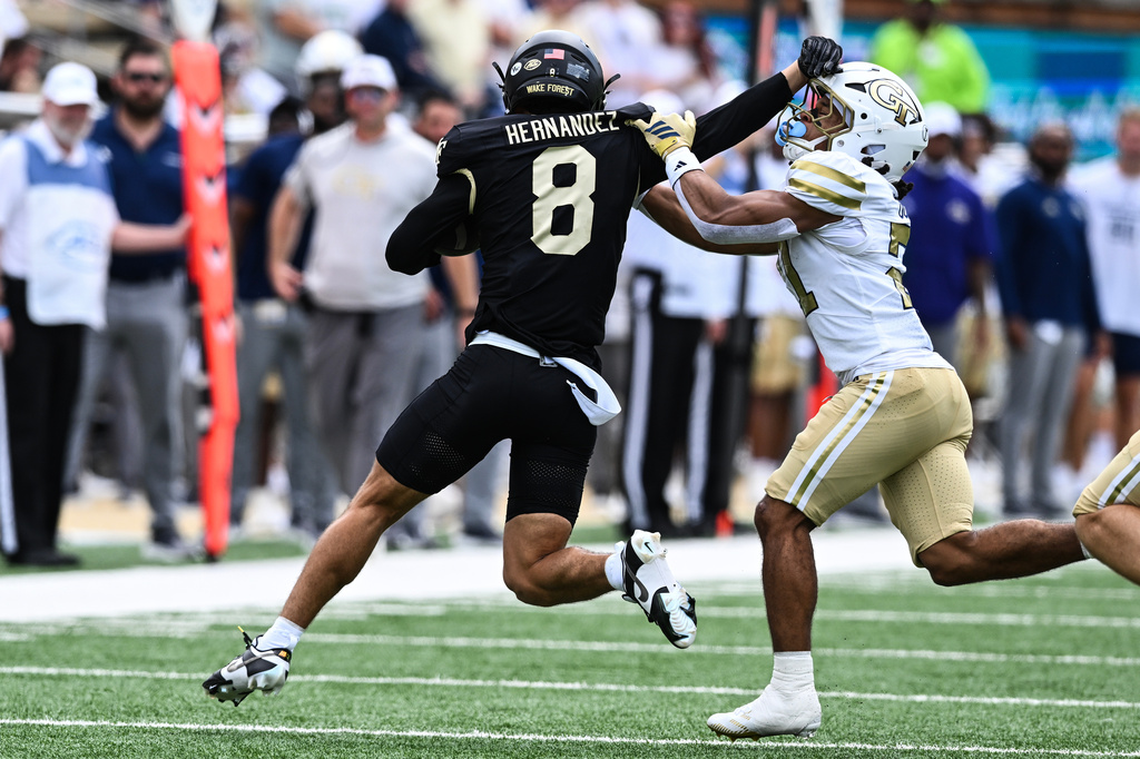 Wake Forest wide receiver Carlos Hernandez (8) stiff arms Georgia Tech defensive back Elgin Sessions (21) during the first half of an NCAA college football game, Saturday, Sept. 27, 2025, in Winston-Salem, N.C. (AP Photo/Matt Kelley)