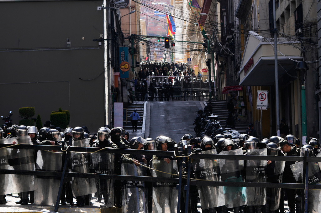Police stand guard behind a fence during anti-government protests near the government palace in La Paz, Bolivia, Monday, May 18, 2026. (AP Photo/Juan Karita)