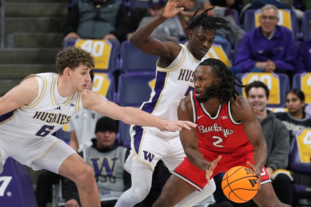 Ohio State guard Bruce Thornton (2) drives to the basket against Washington forward Hannes Steinbach (6) and guard Zoom Diallo (5) during the first half of an NCAA college basketball game Sunday, Jan. 11, 2026, in Seattle. (AP Photo/Lindsey Wasson)