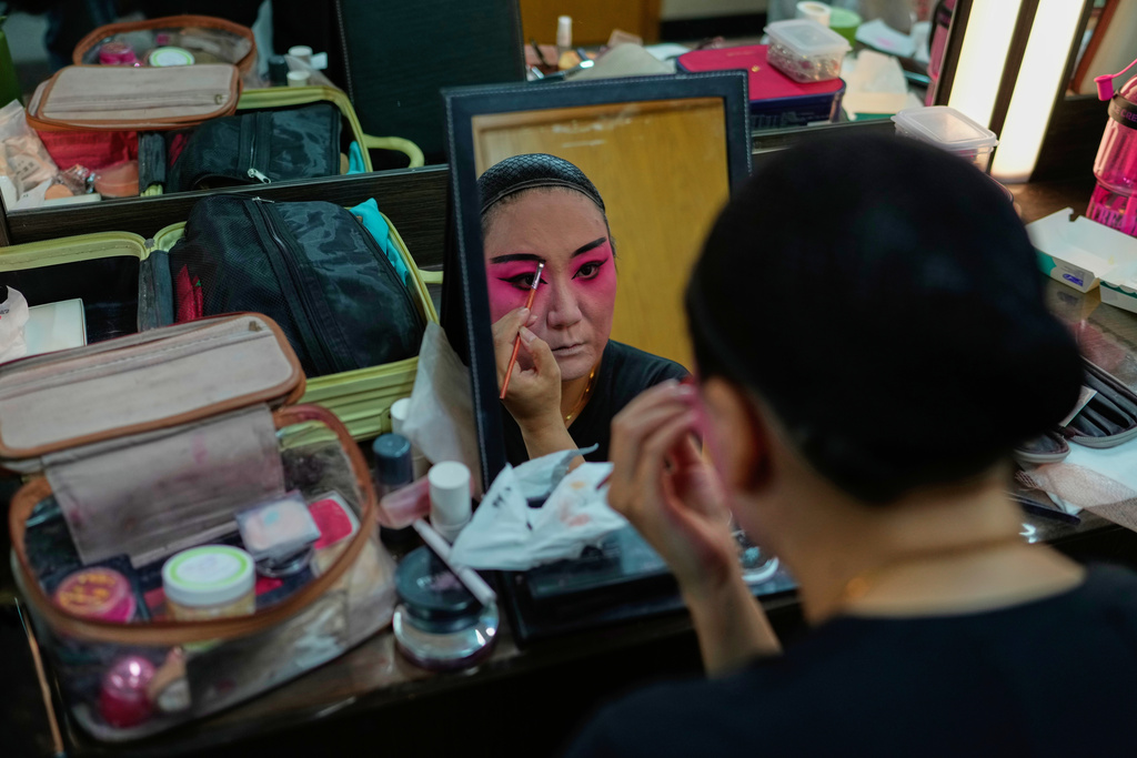 A Peking Opera actress applies makeup backstage before a show in Beijing, China, Sunday, Sept. 7, 2025. (AP Photo/Mahesh Kumar A.)