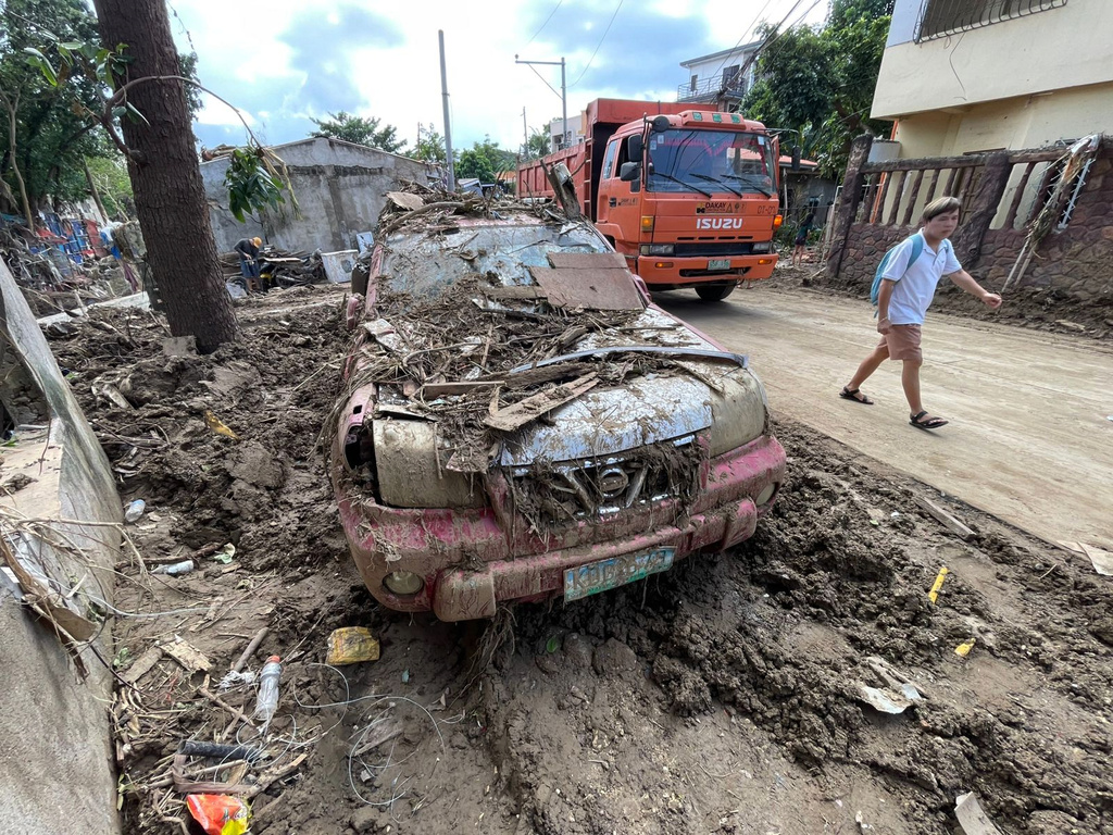 A man passes by a debris laden car as residents return to their flood damaged homes in Bacayan, Cebu province, central Philippines on Friday Nov. 7, 2025 after Typhoon Kalmaegi devastated the province and claimed lives. (AP Photo/Jacqueline Hernandez)