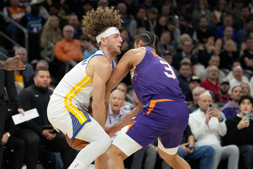 Golden State Warriors guard Brandin Podziemski, left, collides with Phoenix Suns forward Dillon Brooks (3) as they go after a loose ball during the first half of an NBA basketball game Thursday, Dec. 18, 2025, in Phoenix. (AP Photo/Ross D. Franklin)