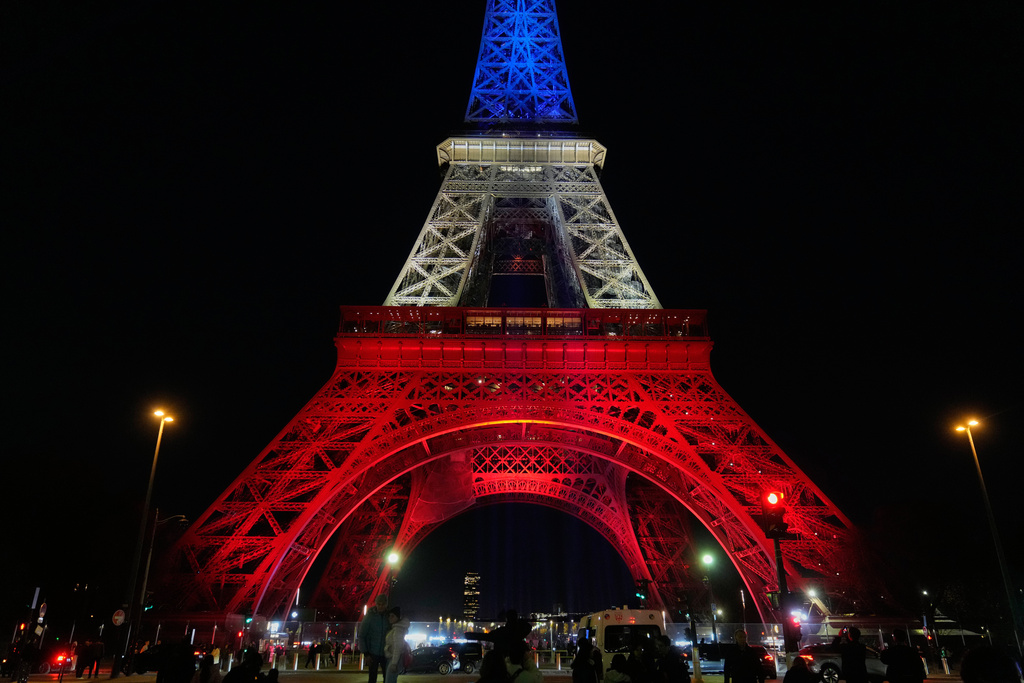 The Eiffel Tower is lit in the colors of the French national flag in Paris, Wednesday, Nov. 12, 2025, to honor the victims of the terror attacks at the Bataclan concert hall, cafes, and the national stadium 10 years ago. (AP Photo/Michel Euler)