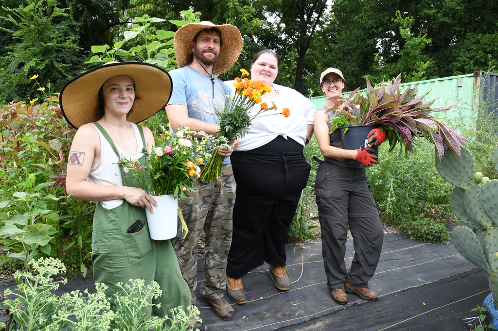 Midtown Bramble & Bloom staff, from left, Courtney Sanderson, Chase Baltz, Marisa Mender-Franklin and Mary Carnes pose with flowers gathered at a crowdsourced garden plot on Thursday, July 23, 2026 in Memphis, Tenn. (AP Photo/Kristin M. Hall)