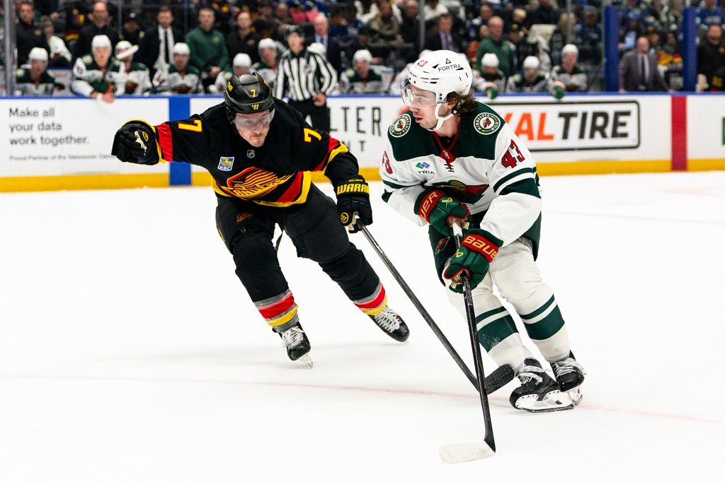 Minnesota Wild's Quinn Hughes (43) skates past Vancouver Canucks' Brendan Gallagher (7) during the second period of an NHL hockey game, in Vancouver, British Columbia, Sunday, Oct. 25, 2026. (Jacob Mallari/The Canadian Press via AP)