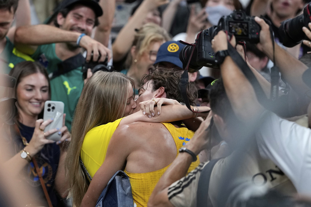 Sweden's Armand Duplantis kisses his girlfriend Desire Inglander after setting a new men's pole vault world record of 6.30 meters, at the World Athletics Championships in Tokyo, Monday, Sept. 15, 2025. (AP Photo/Matthias Schrader)