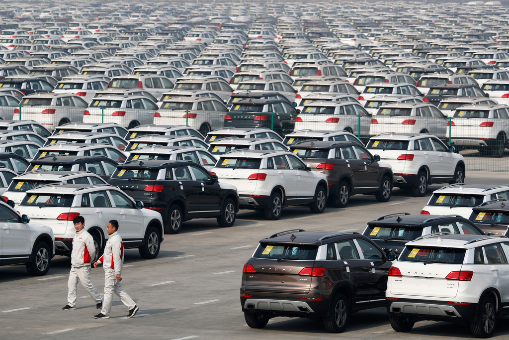 FILE - In this Feb. 19, 2017 file photo, workers walk past Haval SUV models parked outside the Great Wall Motors assembly plant in Baoding in north China's Hebei province. (AP Photo/Andy Wong, File)