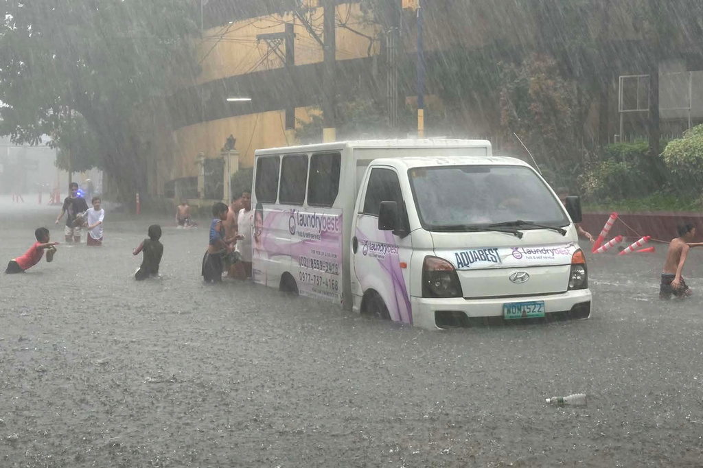 A vehicle passes by a flooded street due to heavy monsoon rains at Mandaluyong, Metro Manila, Philippines, Monday, Aug. 17, 2026. (AP Photo/Joeal Calupitan)