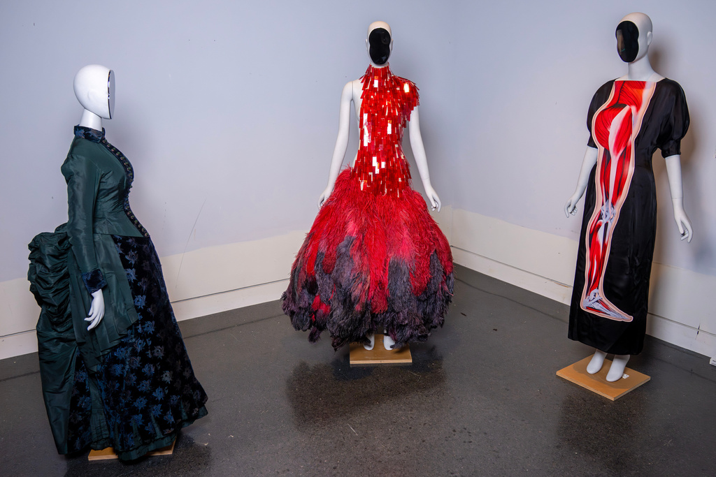 A vintage walking dress, from left, an Alexander McQueen dress, and a Christopher Kane dress are held in preparation for The Metropolitan Museum of Art's spring exhibition, "Costume Art," on Thursday, Feb. 12, 2026, in New York. (Photo by Charles Sykes/Invision/AP)