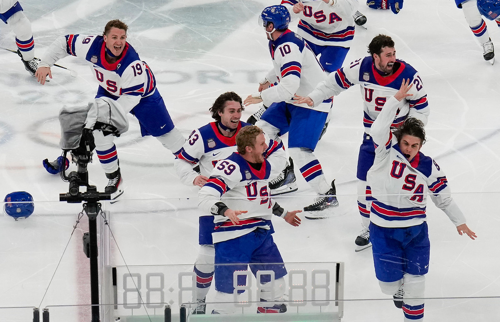 United States' Jack Hughes (86), right, celebrates with teammates after scoring the game winning goal against Canada in sudden death overtime during the men's ice hockey gold medal game at the 2026 Winter Olympics, in Milan, Italy, Sunday, Feb. 22, 2026. (AP Photo/Luca Bruno)