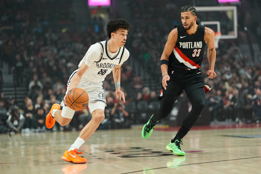 Brooklyn Nets guard Nolan Traore (88) tooks to get past Portland Trail Blazers forward Toumani Camara (33) during the first half of an NBA basketball game Monday, March 23, 2026, in Portland, Ore. (AP Photo/Jenny Kane)