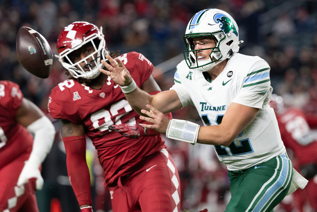 Tulane quarterback Jake Retzlaff, right, tosses the ball past Temple defensive end Khalil Poteat, left, during the first half of an NCAA college football game, Saturday, Nov. 22, 2025, in Philadelphia. (AP Photo/Laurence Kesterson)