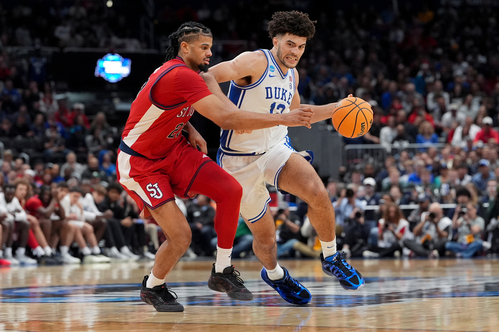 Duke forward Cameron Boozer (12) drives as St. John's forward Bryce Hopkins (23) defends during the second half in the Sweet 16 of the NCAA college basketball tournament, Friday, March 27, 2026, in Washington. (AP Photo/Stephanie Scarbrough)