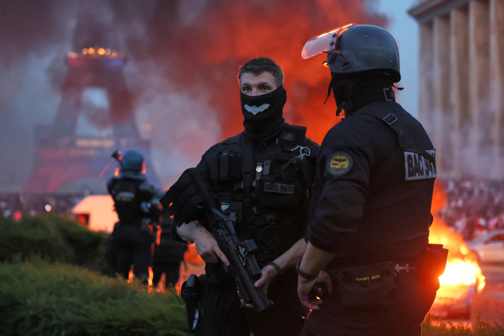A car burns and fireworks explode as police watch PSG supporters celebrate in Paris, Saturday, May 30, 2026 after the Champions League final soccer match between Paris Saint-Germain and Arsenal that was played in Budapest. (AP Photo/Thomas Padilla)