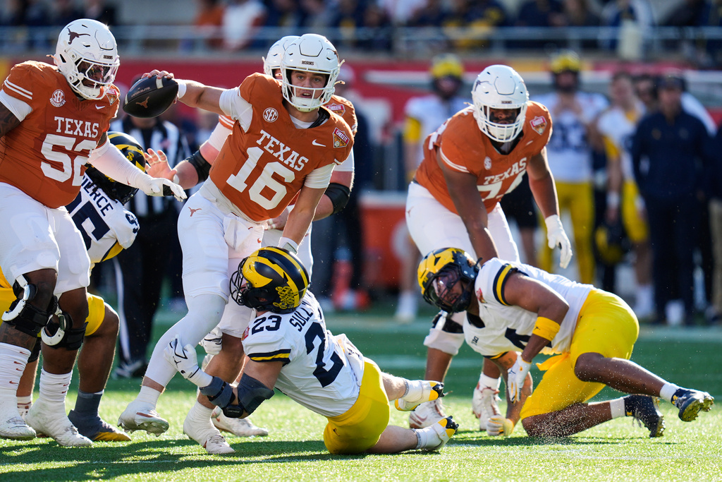 Texas quarterback Arch Manning (16) scrambles before he is stopped by Michigan linebacker Cole Sullivan (23) during the first half of the Citrus Bowl NCAA college football game, Wednesday, Dec. 31, 2025, in Orlando, Fla. (AP Photo/John Raoux)