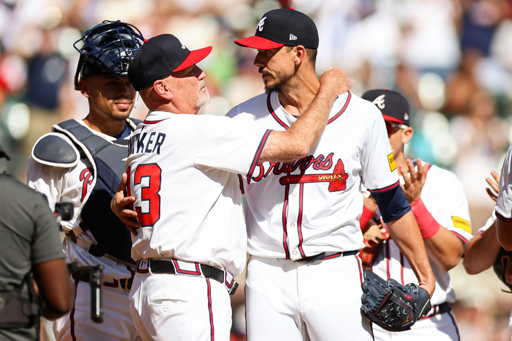 Atlanta Braves manager Brian Snitker, front left, hugs pitcher Charlie Morton, front right, during the second inning of a baseball game against the Pittsburgh Pirates, Sunday, Sept. 28, 2025, in Atlanta. (AP Photo/Colin Hubbard)
