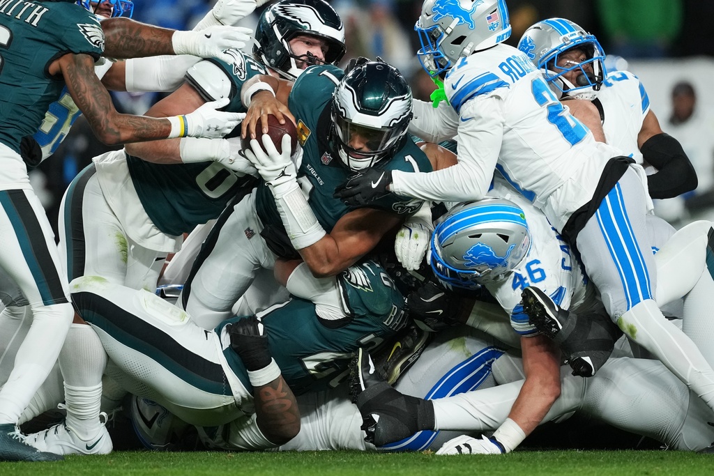 Philadelphia Eagles quarterback Jalen Hurts (1) is stopped with the ball during the second half of an NFL football game by Detroit Lions linebacker Jack Campbell (46) and Lions cornerback Amik Robertson (21) on Sunday, Nov. 16, 2025, in Philadelphia. (AP Photo/Matt Slocum)