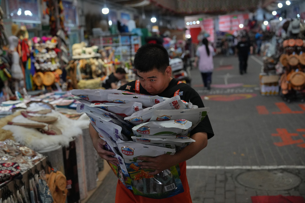 A worker carries packaging of local specialty products inside the Jinshan market in Altay Prefecture, northwest China's Xinjiang Uyghur Autonomous Region, Wednesday, June 10, 2026. (AP Photo/Andy Wong)
