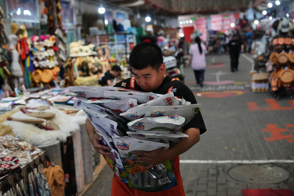 A worker carries packaging of local specialty products at Jinshan market in Altay prefecture, in the northwest Xinjiang Uyghur Autonomous Region of China, Wednesday, June 10, 2026. (AP Photo/Andy Wong)
