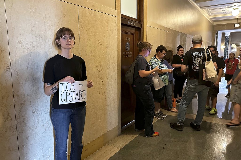 Emily Pietrzak holds a sign that reads "ICE=Gestapo" as other protesters gather outside the Nebraska governor's office in Lincoln, Neb., Tuesday, Aug. 19, 2025. "I believe our government is hurting people who live in our country and I think we should stand up for each other," she said. (AP Photo/Josh Funk)