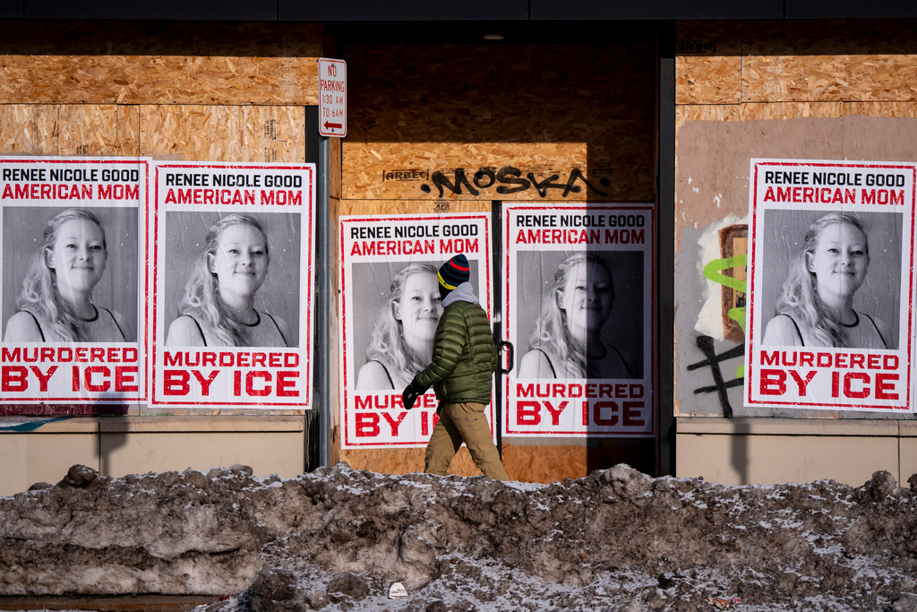 A person walks past signage for Renee Good, who was fatally shot by an ICE officer earlier in the week, in Minneapolis, Minn., Sunday, Jan. 11, 2026. (Christopher Katsarov/The Canadian Press via AP)