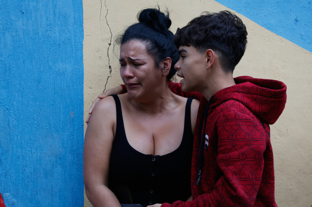 A boy comforts his mother after an earthquake in Caracas, Venezuela, Wednesday, June 24, 2026. (AP Photo/Pedro Mattey)