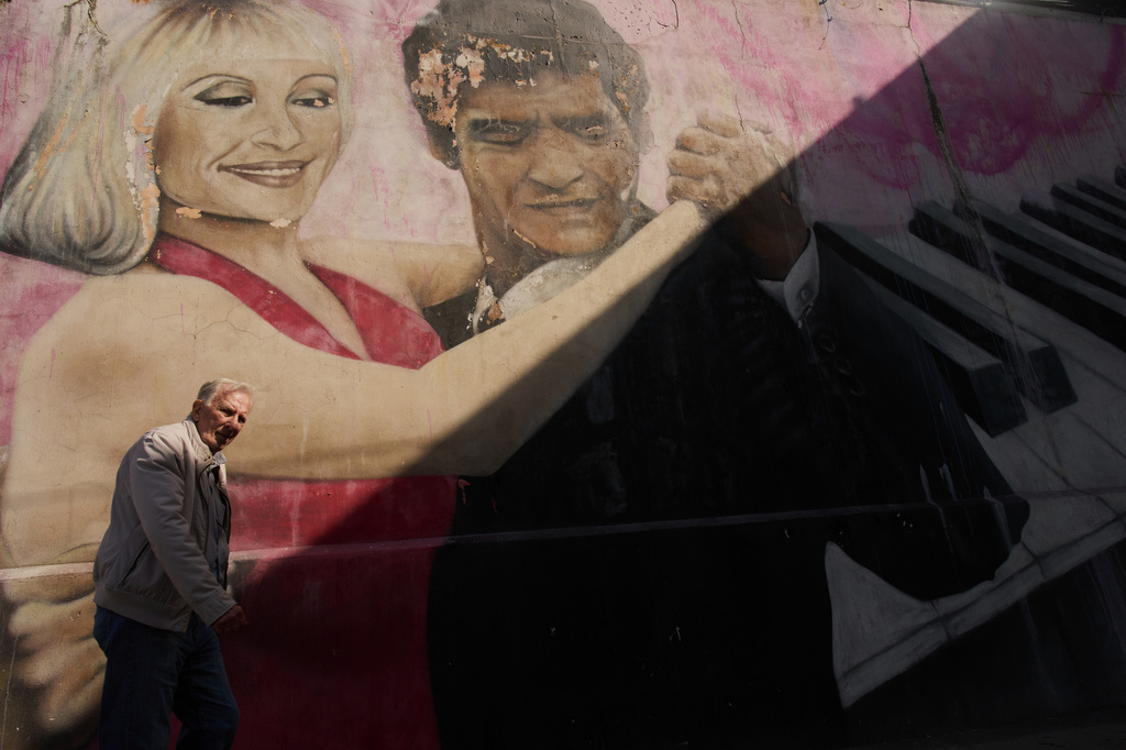 A man walks past a mural by artist Alfredo Segatori depicting late soccer legend Diego Maradona and Italian singer Raffaella Carra dancing tango, in Buenos Aires, Argentina, Monday, April 13, 2026. (AP Photo/Rodrigo Abd)