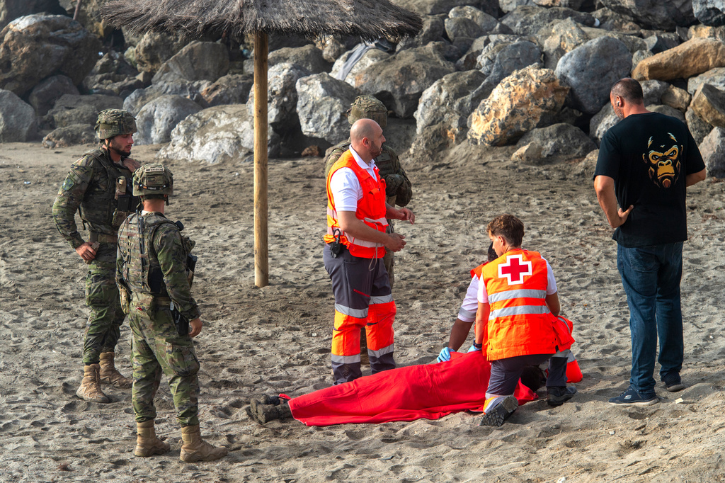 Spanish army soldiers and Red Cross workers assist a migrant who swam from Morocco to the Spanish enclave of Ceuta, Saturday, Aug. 1, 2026. (AP Photo/Antonio Sempere)