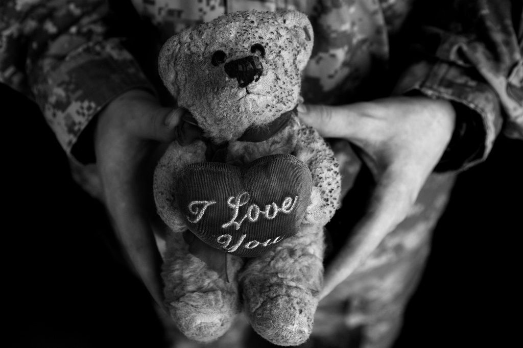 FILE - U.S. Army Sgt. Jon Fleenor from Sacramento, Calif., holds his scorched teddy bear, given to him by his wife, which he carries as a good-luck charm in Mosul, northwest of Baghdad, Iraq, March 27, 2008. (AP Photo/Maya Alleruzzo, File)