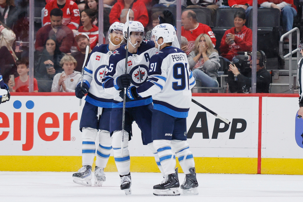 Winnipeg Jets center Cole Perfetti (91) celebrates after his goal against the Detroit Red Wings with left wing Kyle Connor, left, and center Mark Scheifele (55) during the first period of an NHL hockey game Sunday, Oct. 4, 2026, in Detroit. (AP Photo/Duane Burleson)