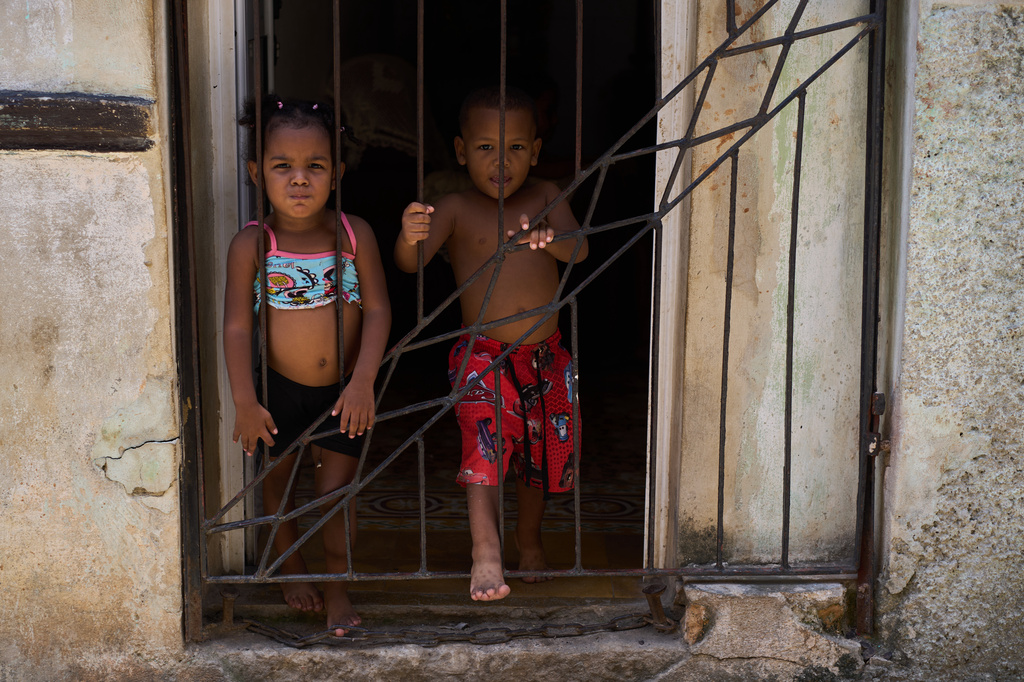 Children cool off in their doorway during a blackout in Havana, Cuba, Tuesday, July 14, 2026. (AP Photo/Ramon Espinosa)