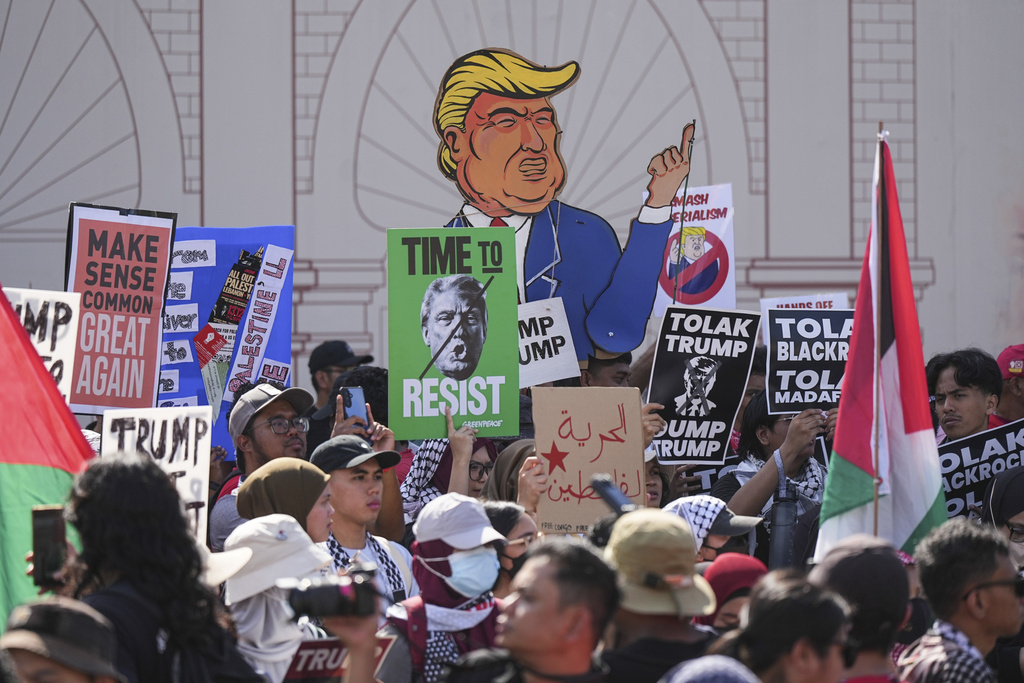 Protesters hold signs during a demonstration against U.S. President Donald Trump's attendance at the Association of Southeast Asian Nations (ASEAN) Summit in Kuala Lumpur, Malaysia, on Sunday, Oct. 26, 2025. (AP Photo/Azneal Ishak)