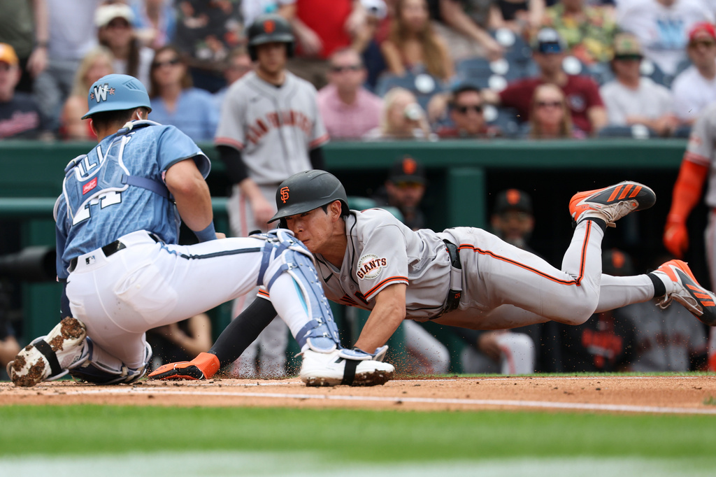 San Francisco Giants' Jung Hoo Lee is tagged out at home plate by Washington Nationals catcher Drew Millas while attempting to score on double hit by San Francisco Giants' Heliot Ramos against pitcher Cade Cavalli during the second inning of a baseball game, Saturday, April 18, 2026, in Washington. (AP Photo/Terrance Williams)